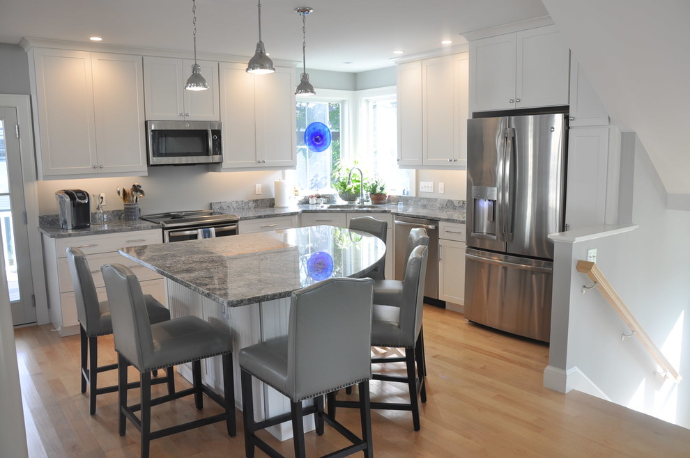 Small transitional l-shaped light wood floor open concept kitchen photo in Boston with an undermount sink, shaker cabinets, white cabinets, granite countertops, gray backsplash, stainless steel appliances, an island and gray countertops