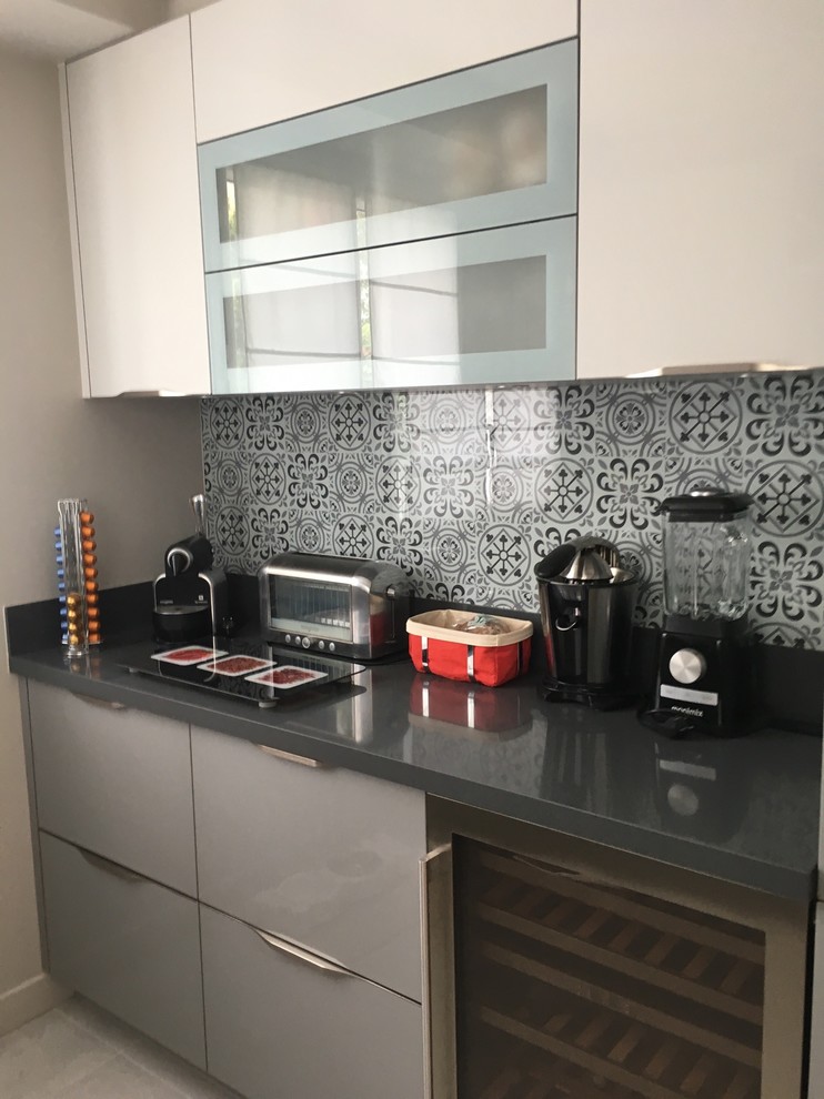 Photo of a mid-sized contemporary galley kitchen in Paris with an undermount sink, beaded inset cabinets, grey cabinets, quartzite benchtops, grey splashback, glass sheet splashback, stainless steel appliances, ceramic floors and grey floor.