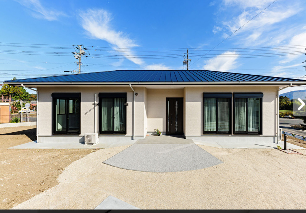Стильный дизайн: одноэтажный, бежевый частный загородный дом с вальмовой крышей и синей крышей - последний тренд