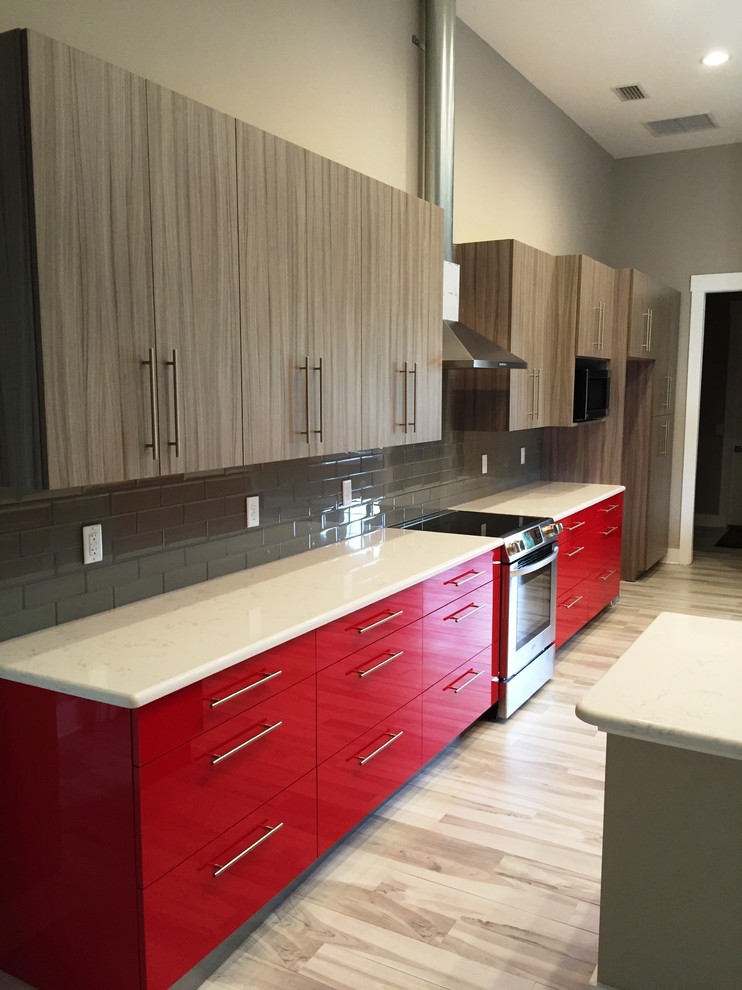 Photo of a large eclectic single-wall open plan kitchen in Jacksonville with an undermount sink, flat-panel cabinets, red cabinets, quartz benchtops, grey splashback, glass tile splashback, stainless steel appliances, porcelain floors and with island.