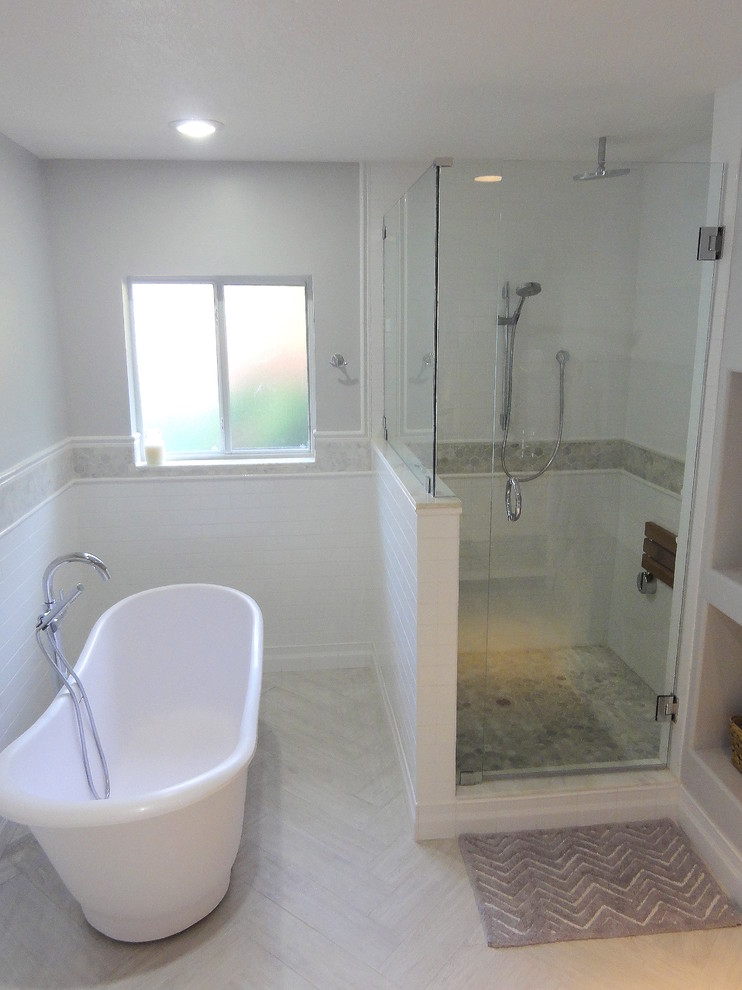 На фото: большая главная ванная комната в стиле неоклассика (современная классика) с белыми фасадами, отдельно стоящей ванной, душем в нише, раздельным унитазом, белой плиткой, керамической плиткой, серыми стенами и полом из керамогранита