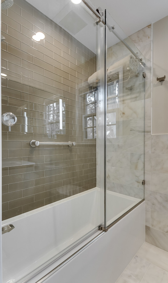 This is an example of a mid-sized transitional kids bathroom in DC Metro with flat-panel cabinets, white cabinets, an alcove tub, a shower/bathtub combo, a one-piece toilet, multi-coloured tile, beige walls, marble floors, a wall-mount sink, glass benchtops, multi-coloured floor and a sliding shower screen.