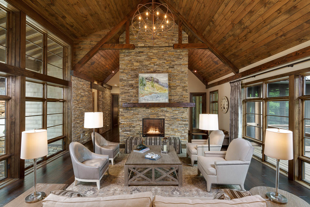 Large country open concept living room in Other with beige walls, dark hardwood floors, a two-sided fireplace and a stone fireplace surround.