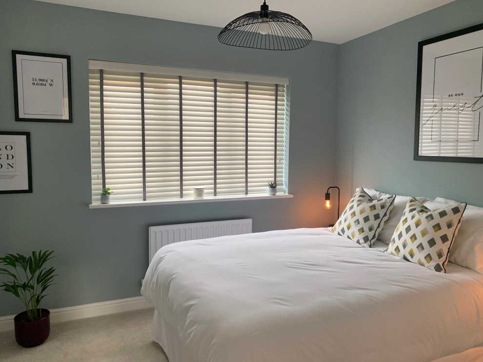 Mid-sized modern guest bedroom in Hertfordshire with blue walls, carpet and beige floor.