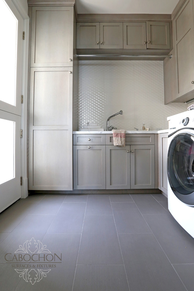 Design ideas for a large transitional u-shaped dedicated laundry room in San Diego with an undermount sink, recessed-panel cabinets, grey cabinets, marble benchtops, white walls, porcelain floors and a side-by-side washer and dryer.