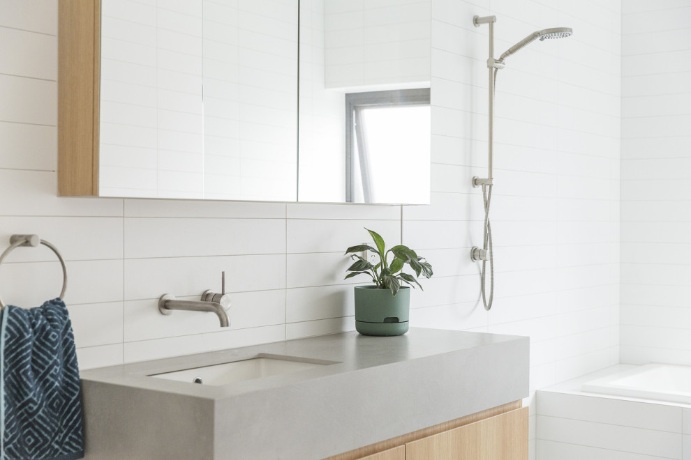 Inspiration for a contemporary bathroom in Melbourne with flat-panel cabinets, medium wood cabinets, a drop-in tub, white tile, an undermount sink, grey benchtops, a single vanity and a floating vanity.