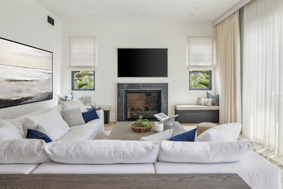 Großes, Offenes Mediterranes Wohnzimmer mit weißer Wandfarbe, hellem Holzboden, Kamin, Kaminumrandung aus Stein, Multimediawand und beigem Boden in Los Angeles