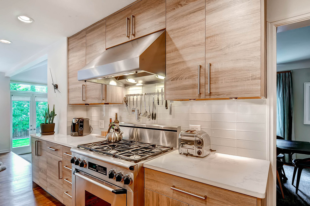 Design ideas for a large contemporary u-shaped eat-in kitchen in Denver with a double-bowl sink, flat-panel cabinets, light wood cabinets, quartz benchtops, white splashback, subway tile splashback, stainless steel appliances, medium hardwood floors and with island.