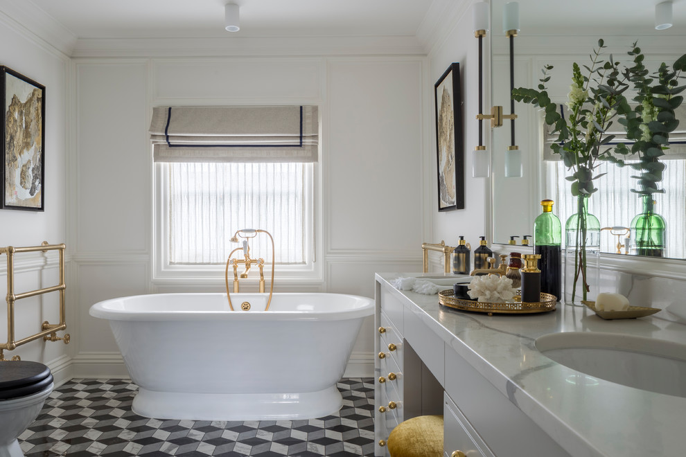This is an example of a mid-sized eclectic bathroom in London with flat-panel cabinets, grey cabinets, a freestanding tub, a one-piece toilet, ceramic floors, an undermount sink, marble benchtops and multi-coloured floor.