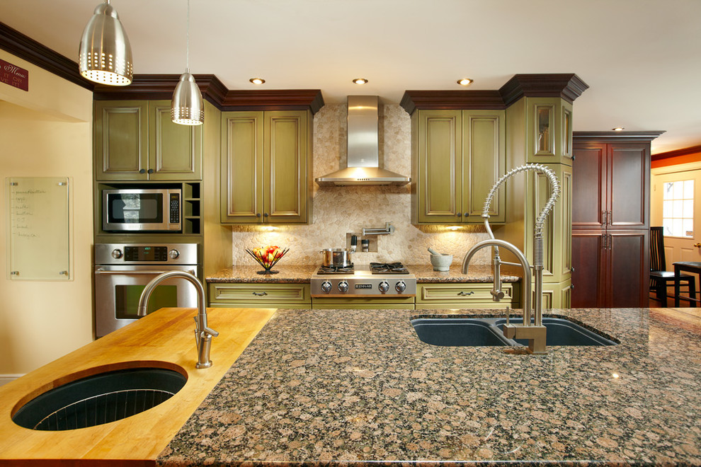 Mid-sized transitional l-shaped light wood floor eat-in kitchen photo in Toronto with an undermount sink, green cabinets, granite countertops, beige backsplash, stone tile backsplash, stainless steel appliances, an island and recessed-panel cabinets