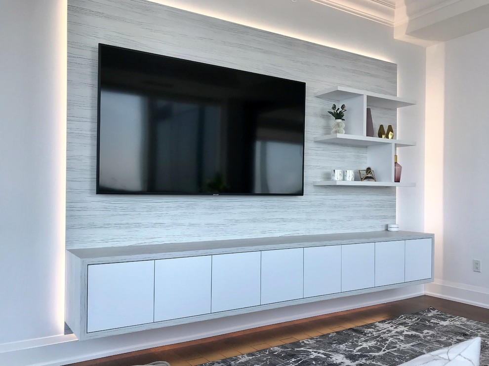 This is an example of a small contemporary open concept living room in Toronto with white walls, light hardwood floors and a built-in media wall.