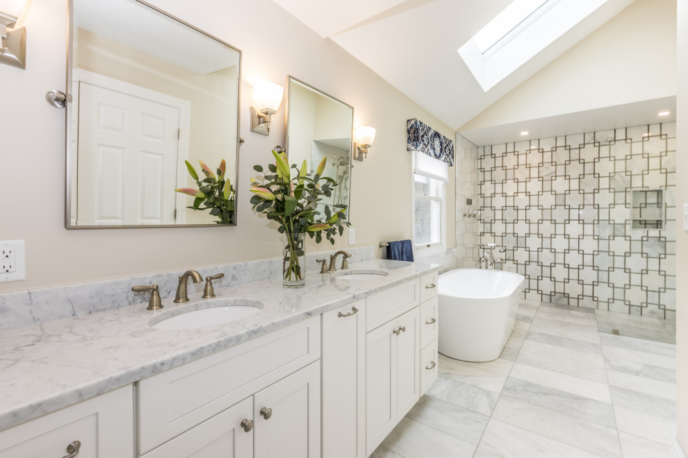 Large transitional master bathroom in Philadelphia with shaker cabinets, white cabinets, a freestanding tub, a curbless shower, a bidet, gray tile, marble, beige walls, marble floors, an undermount sink, marble benchtops, grey floor, an open shower, grey benchtops, a double vanity, a freestanding vanity and vaulted.
