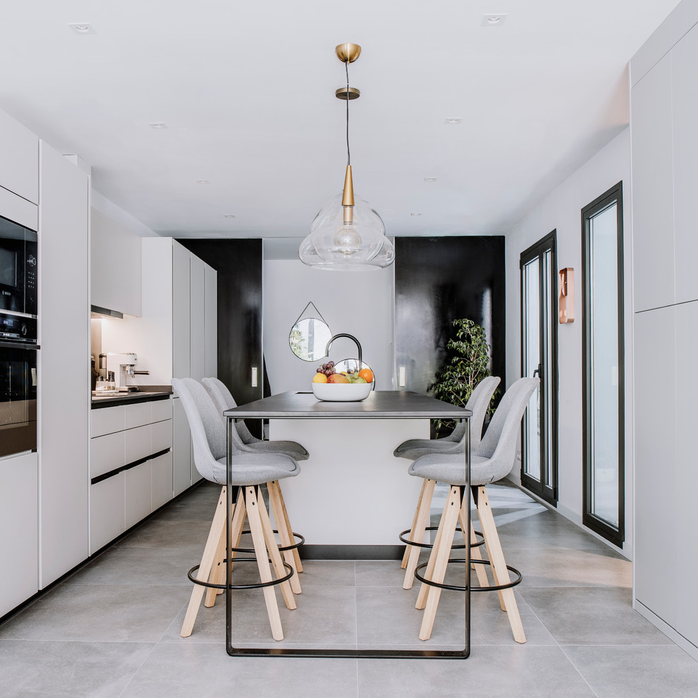 This is an example of a large contemporary galley kitchen in Barcelona with a double-bowl sink, flat-panel cabinets, quartz benchtops, panelled appliances, porcelain floors, with island, grey floor, black benchtop and white cabinets.