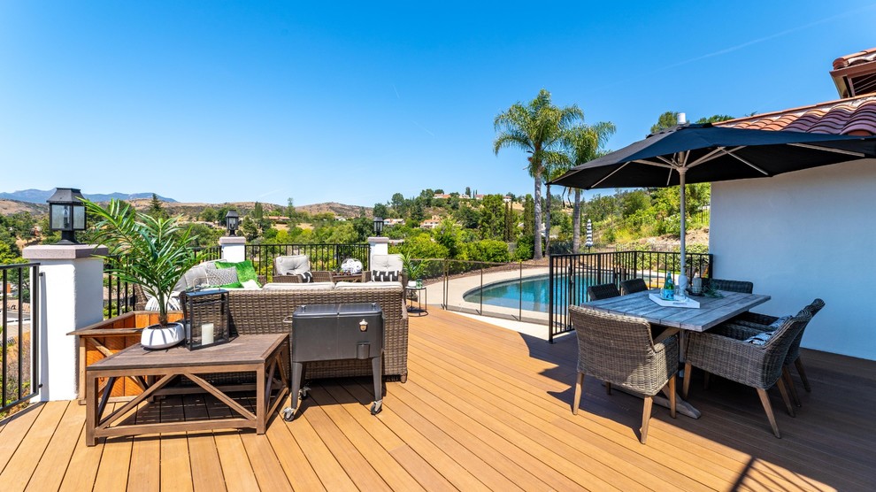Large transitional backyard deck photo with a fire pit