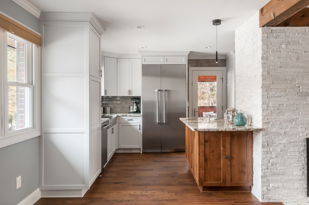 Expansive midcentury eat-in kitchen in Atlanta with a farmhouse sink, shaker cabinets, white cabinets, quartzite benchtops, grey splashback, glass tile splashback, stainless steel appliances, dark hardwood floors, a peninsula, brown floor and white benchtop.