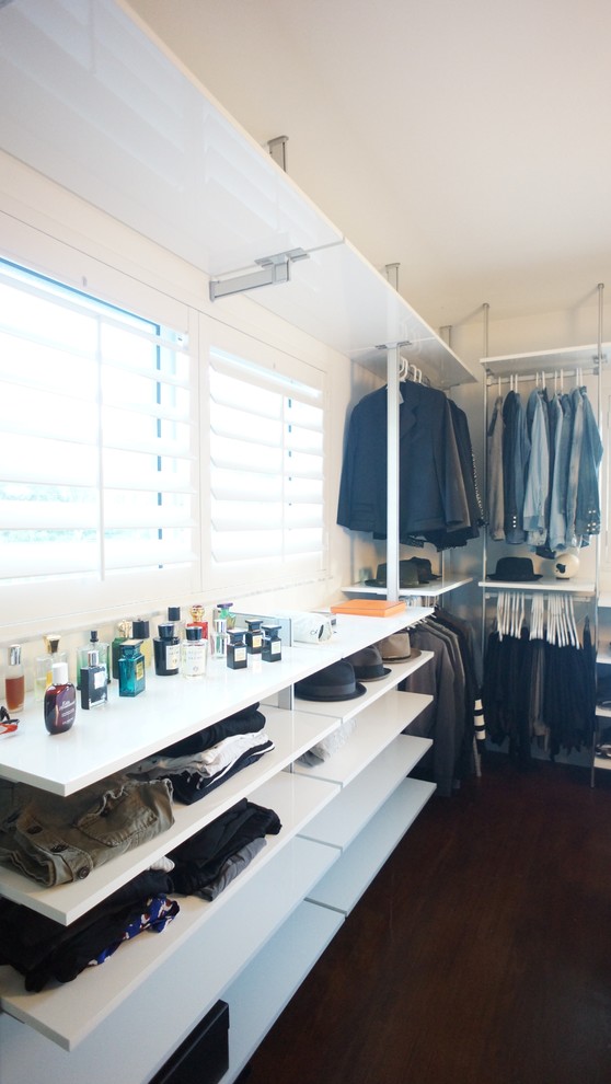 Large modern gender-neutral dressing room in Miami with open cabinets, white cabinets and bamboo floors.