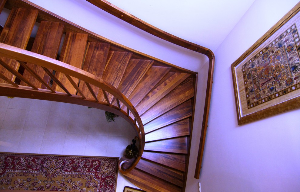 На фото: большая изогнутая лестница в классическом стиле с деревянными ступенями без подступенок с