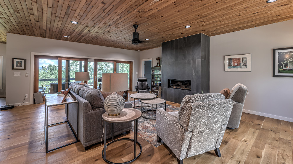Large contemporary open concept living room in Atlanta with grey walls, light hardwood floors, a ribbon fireplace, a tile fireplace surround, no tv, brown floor and wood.