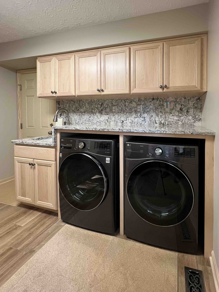 Design ideas for a mid-sized traditional galley dedicated laundry room in Cleveland with an undermount sink, recessed-panel cabinets, light wood cabinets, quartzite benchtops, brown splashback, engineered quartz splashback, beige walls, laminate floors, a side-by-side washer and dryer, beige floor and brown benchtop.