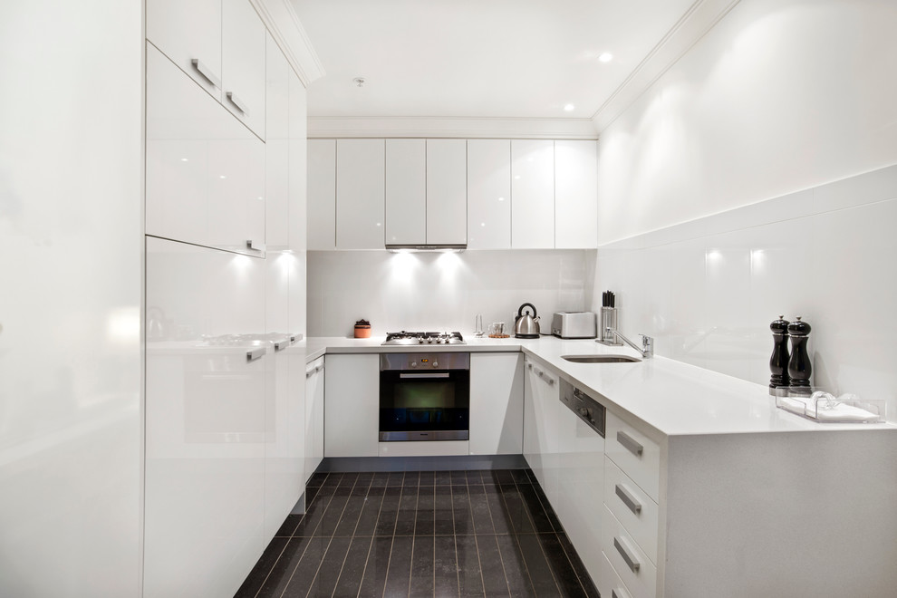 Design ideas for a contemporary u-shaped kitchen in Melbourne with an undermount sink, flat-panel cabinets, white cabinets, white splashback, stainless steel appliances and no island.