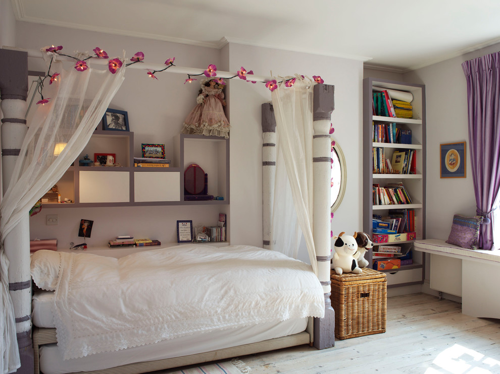 This is an example of a mid-sized transitional kids' bedroom for kids 4-10 years old and girls in London with purple walls and light hardwood floors.