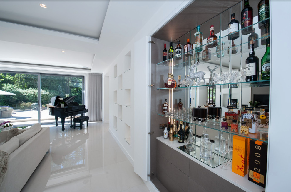 Inspiration for a small contemporary single-wall home bar in Other with flat-panel cabinets, solid surface benchtops, mirror splashback, porcelain floors, white floor and white benchtop.