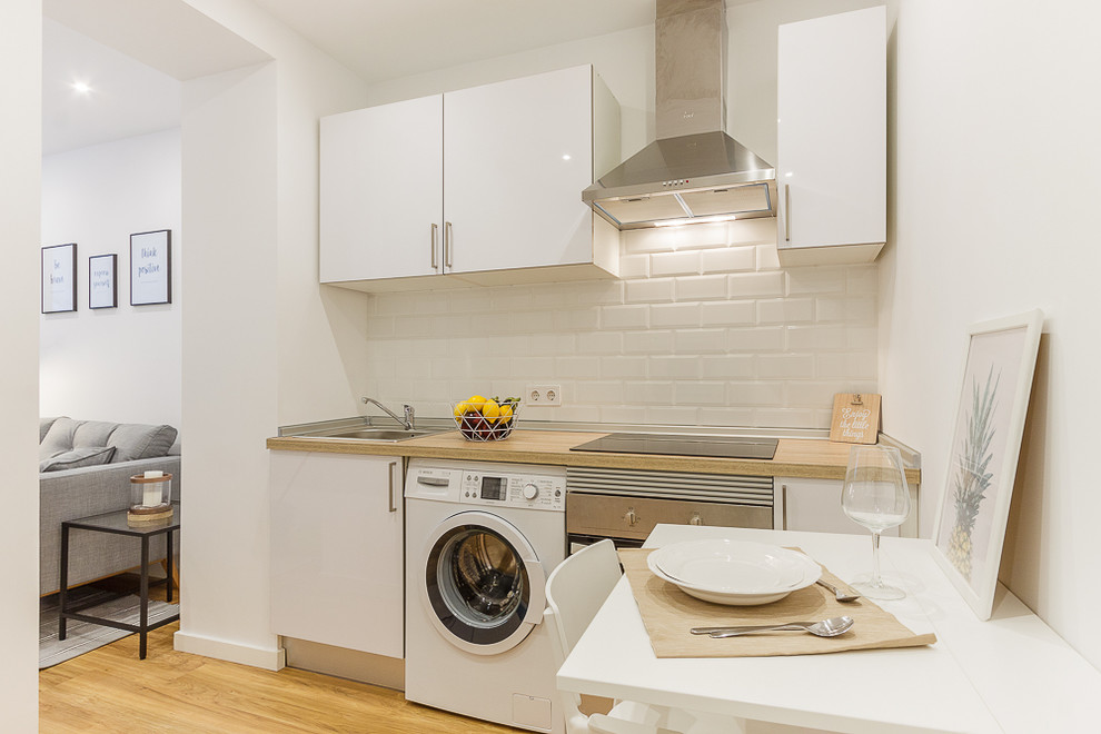 This is an example of a small scandinavian single-wall separate kitchen in Madrid with a single-bowl sink, flat-panel cabinets, white cabinets, wood benchtops, white splashback, subway tile splashback and no island.