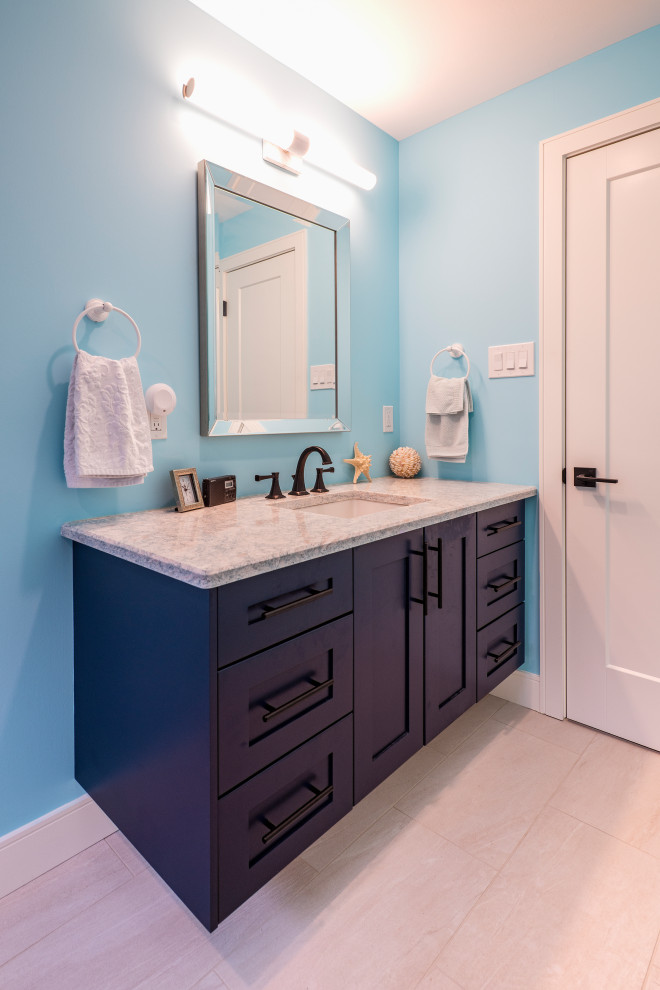 This is an example of a small master bathroom in Toronto with shaker cabinets, blue cabinets, an alcove shower, a one-piece toilet, white tile, ceramic tile, blue walls, ceramic floors, an undermount sink, quartzite benchtops, beige floor, a hinged shower door and grey benchtops.