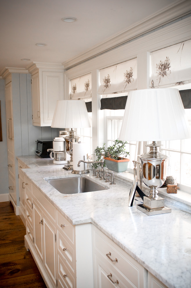 This is an example of a mid-sized country single-wall eat-in kitchen in Manchester with a single-bowl sink, marble benchtops, white cabinets, stainless steel appliances, raised-panel cabinets and dark hardwood floors.