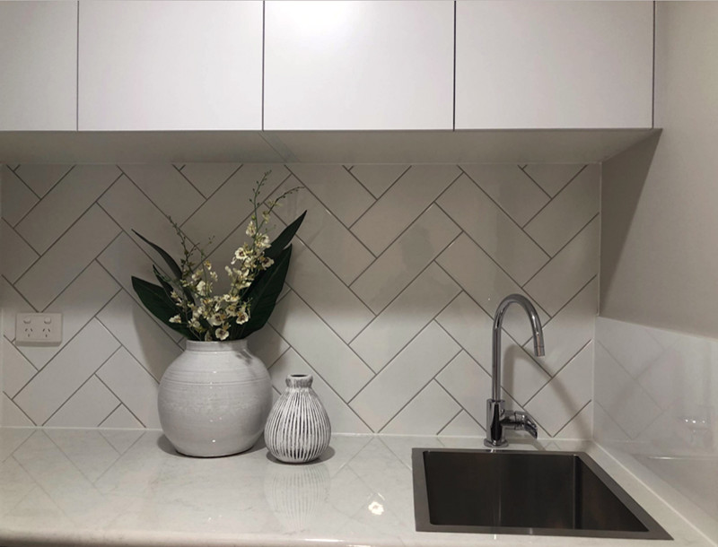 Design ideas for a small transitional l-shaped dedicated laundry room in Brisbane with a single-bowl sink, flat-panel cabinets, white cabinets, laminate benchtops, grey walls, ceramic floors and white floor.