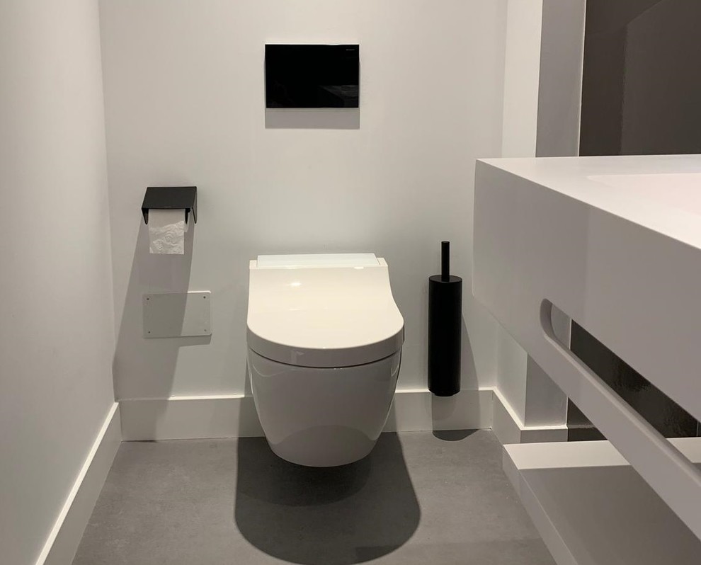 Diseño de aseo minimalista con sanitario de pared, lavabo suspendido, baldosas y/o azulejos blancos y suelo gris