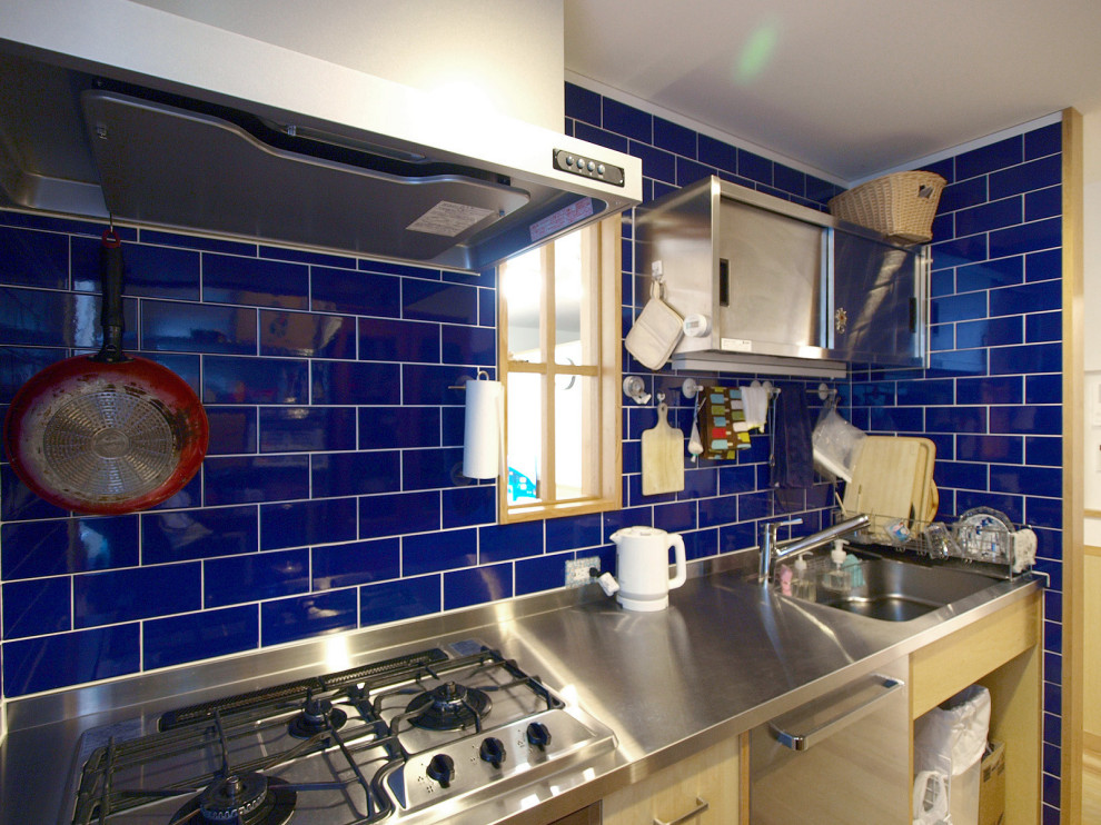 Immagine di una cucina lineare scandinava chiusa con top in acciaio inossidabile