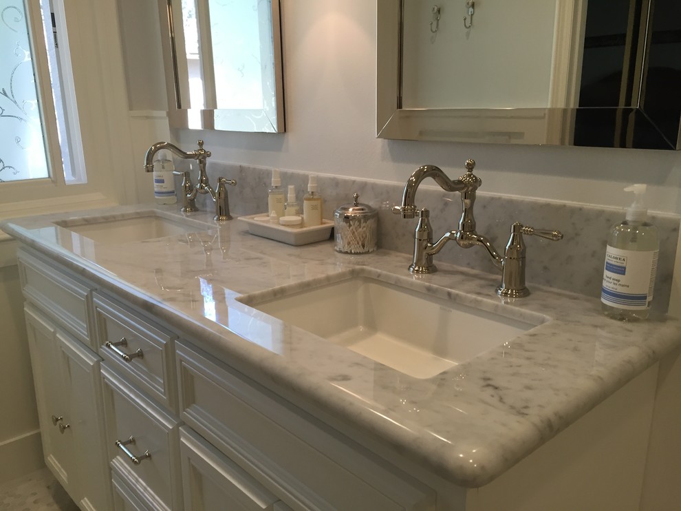 Photo of a beach style bathroom in Orange County with an undermount sink, white cabinets, marble benchtops, black and white tile and marble floors.