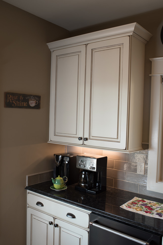 Eat-in kitchen - large rustic l-shaped dark wood floor and brown floor eat-in kitchen idea with a farmhouse sink, raised-panel cabinets, granite countertops, gray backsplash, ceramic backsplash, black appliances, an island and white cabinets