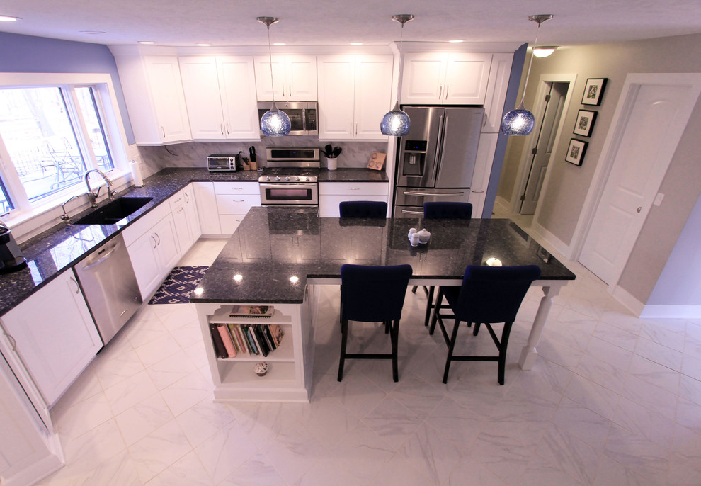 This is an example of a mid-sized transitional l-shaped open plan kitchen in Grand Rapids with a double-bowl sink, raised-panel cabinets, white cabinets, granite benchtops, grey splashback, marble splashback, stainless steel appliances, marble floors, with island, white floor and black benchtop.
