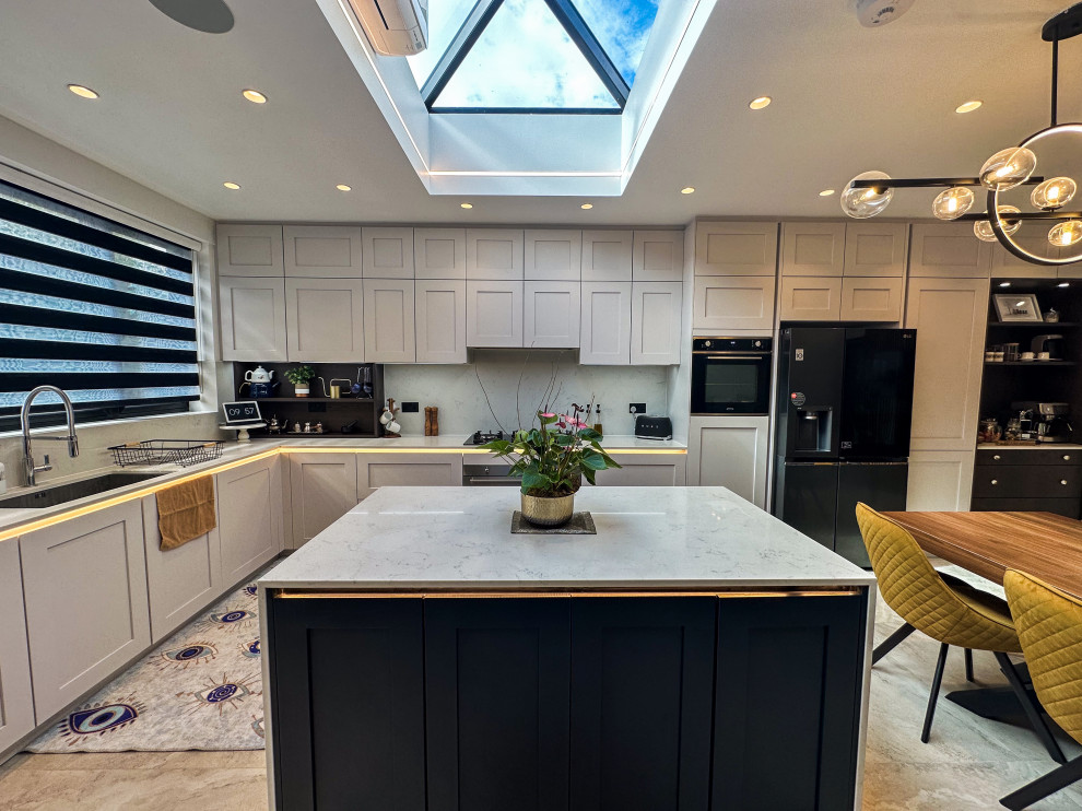 Design ideas for a large traditional l-shaped kitchen/diner in London with a built-in sink, shaker cabinets, blue cabinets, quartz worktops, white splashback, engineered quartz splashback, integrated appliances, porcelain flooring, an island, beige floors, white worktops and feature lighting.