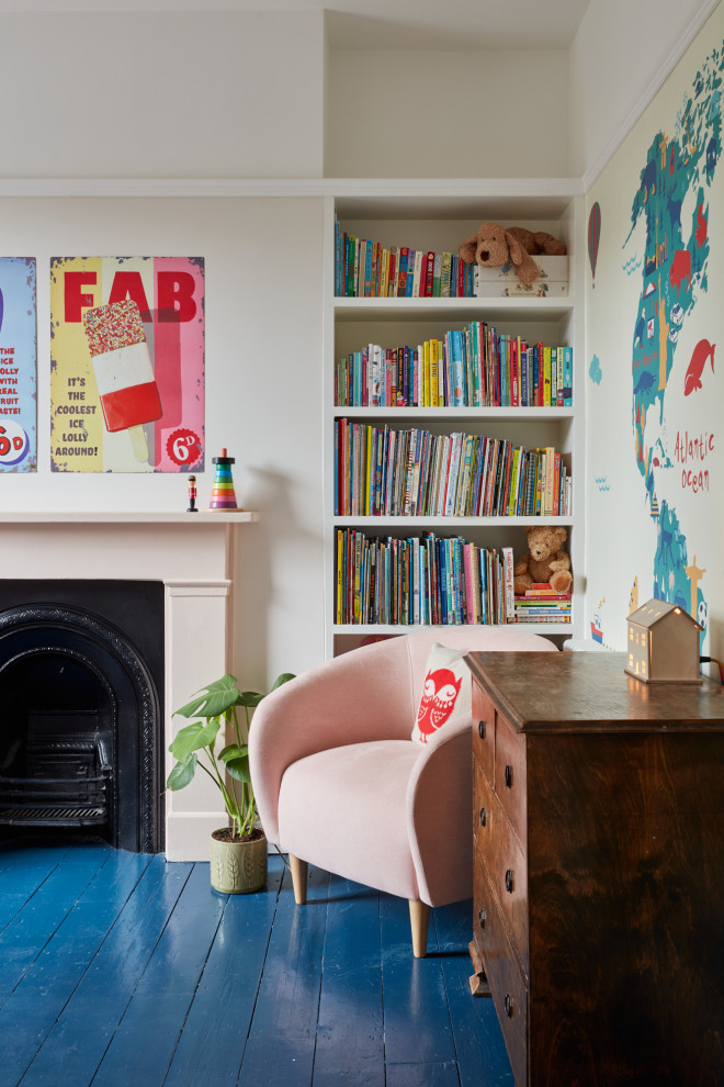 This is an example of a mid-sized eclectic bedroom in London with pink walls, painted wood floors, a standard fireplace, a metal fireplace surround, blue floor and wallpaper.
