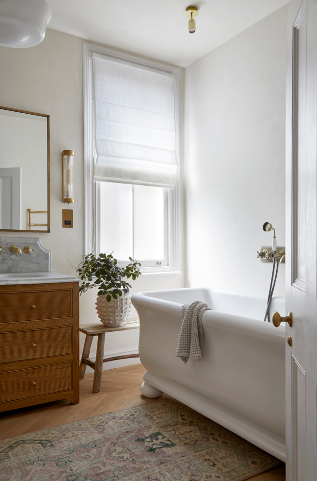 Design ideas for a traditional bathroom in Other with beaded inset cabinets, medium wood cabinets, a freestanding tub, medium hardwood floors, an undermount sink, brown floor, grey benchtops and a freestanding vanity.