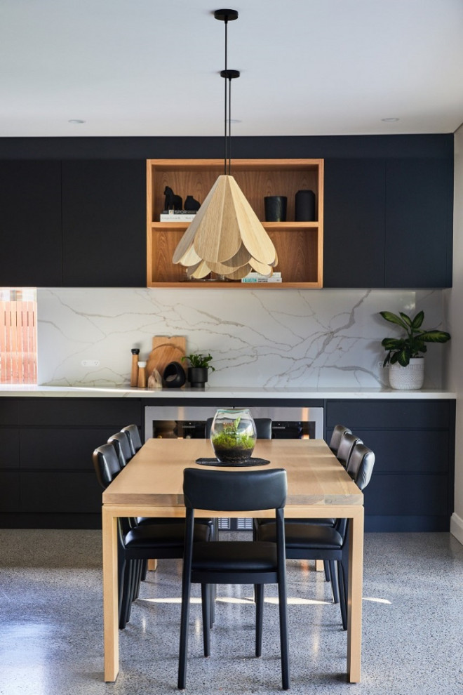 This is an example of a contemporary galley eat-in kitchen in Sydney with black cabinets, quartz benchtops, white splashback, engineered quartz splashback, with island and white benchtop.