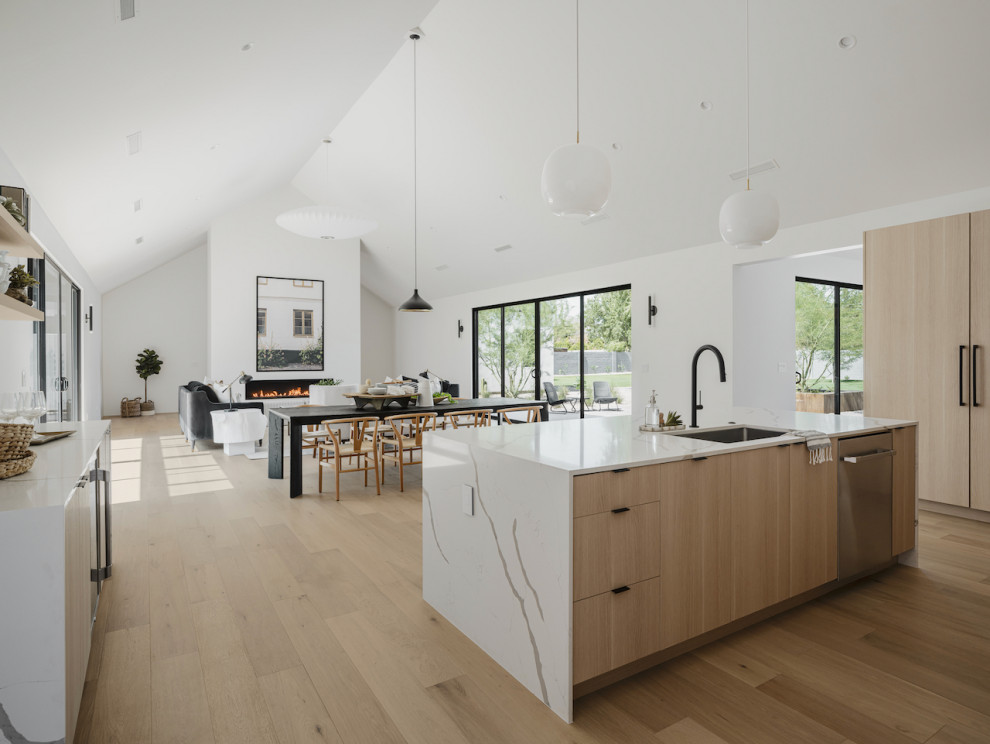 Inspiration for a scandinavian open plan kitchen in Phoenix with a single-bowl sink, flat-panel cabinets, light wood cabinets, quartz benchtops, white splashback, porcelain splashback, panelled appliances, light hardwood floors, with island, white benchtop and vaulted.
