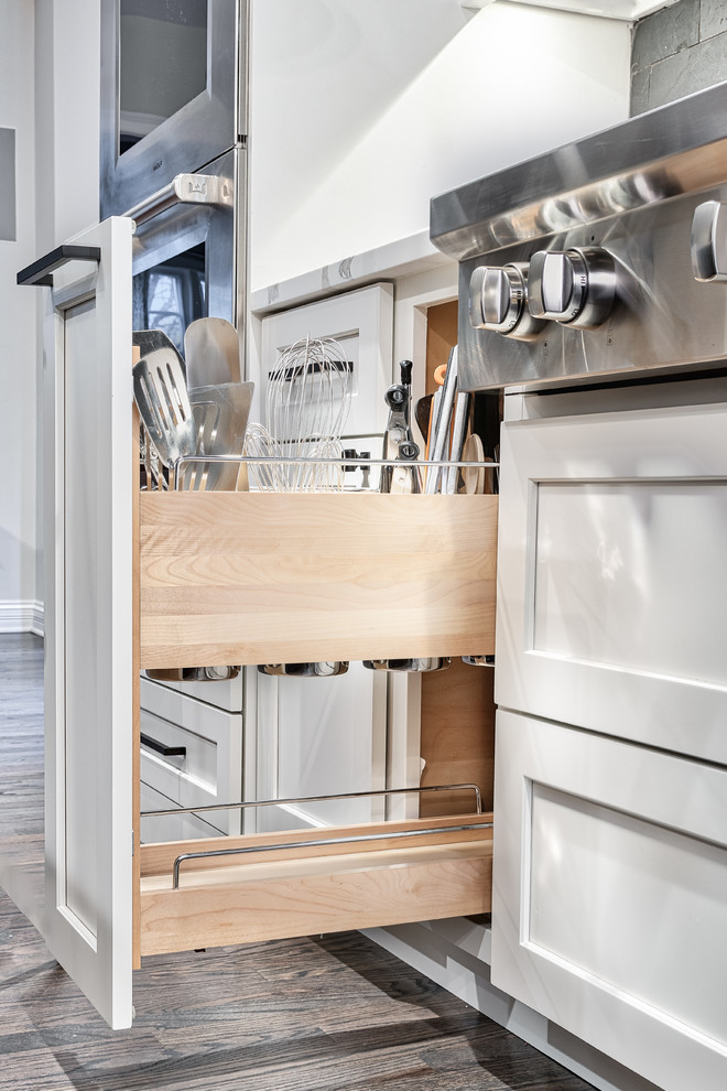 Large transitional u-shaped medium tone wood floor and brown floor kitchen pantry photo in Nashville with an undermount sink, shaker cabinets, dark wood cabinets, solid surface countertops, black backsplash, brick backsplash, stainless steel appliances, an island and white countertops