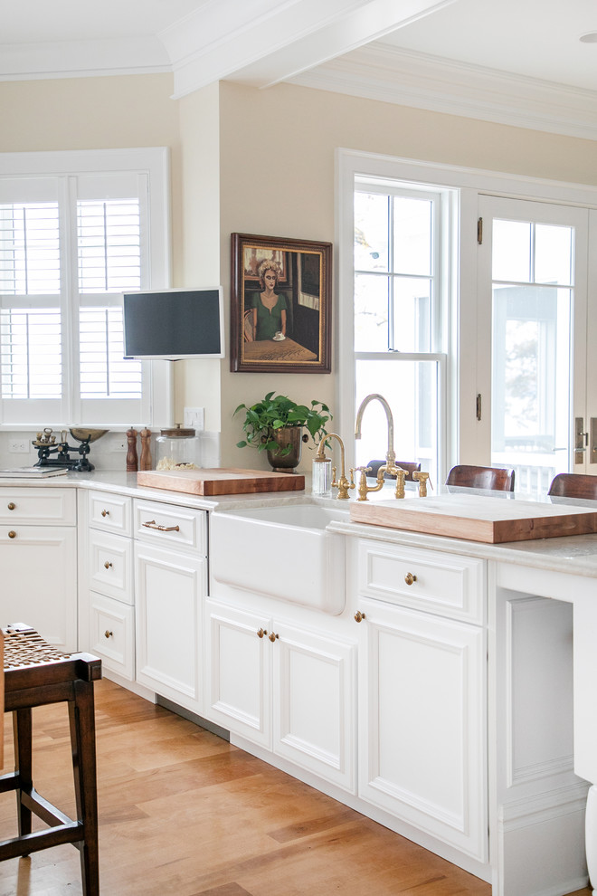 Large country u-shaped open plan kitchen in Milwaukee with a farmhouse sink, recessed-panel cabinets, white cabinets, white splashback, subway tile splashback, white appliances, light hardwood floors, with island, beige floor and grey benchtop.