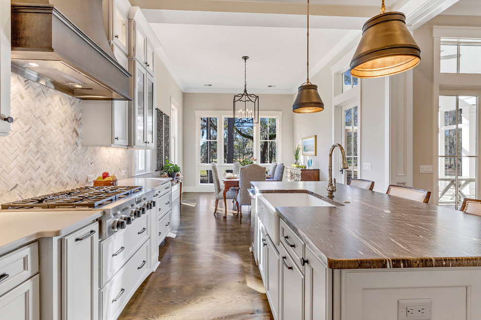 Large country l-shaped kitchen in Charleston with a farmhouse sink, recessed-panel cabinets, white cabinets, white splashback, mosaic tile splashback, stainless steel appliances, dark hardwood floors, with island, brown floor and brown benchtop.