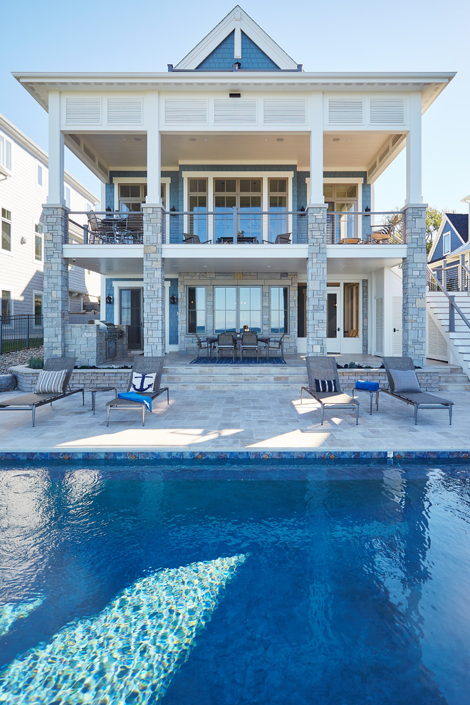 Inspiration for a mid-sized traditional backyard rectangular infinity pool in Grand Rapids with natural stone pavers.