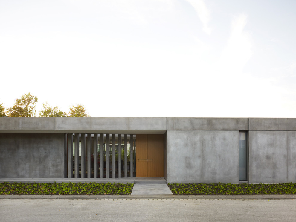 This is an example of a mid-sized industrial one-storey concrete grey house exterior in Other with a flat roof.