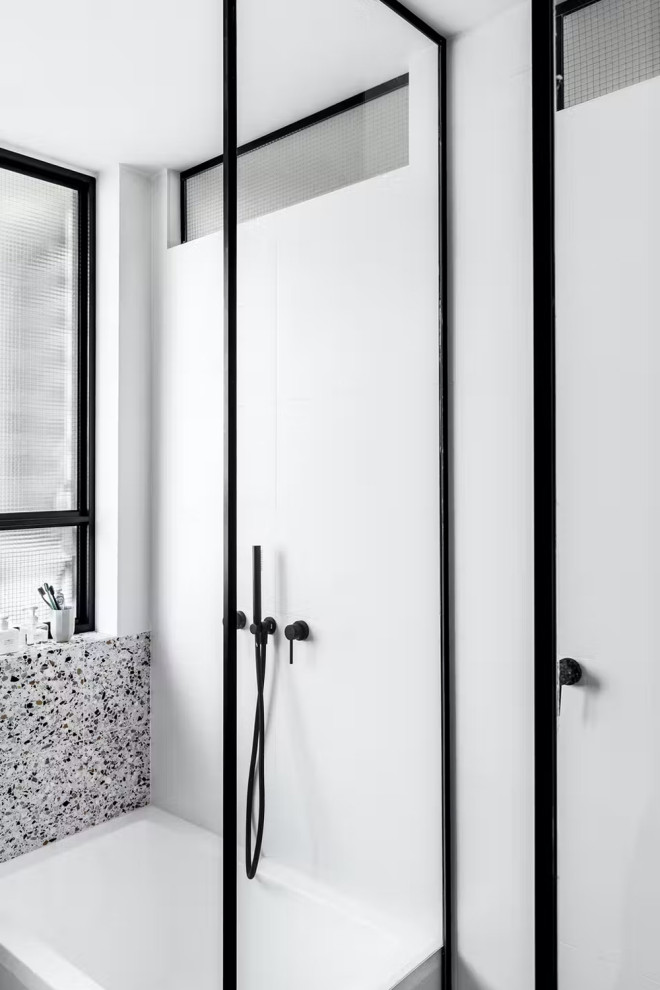 Aménagement d'une petite salle d'eau avec une douche d'angle, un carrelage blanc, du carrelage en marbre, un mur blanc, un sol en terrazzo, une vasque, un sol blanc et une cabine de douche à porte coulissante.