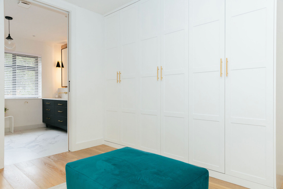 Idée de décoration pour une chambre parentale grise et blanche tradition de taille moyenne avec un mur blanc, un sol en bois brun et un sol beige.