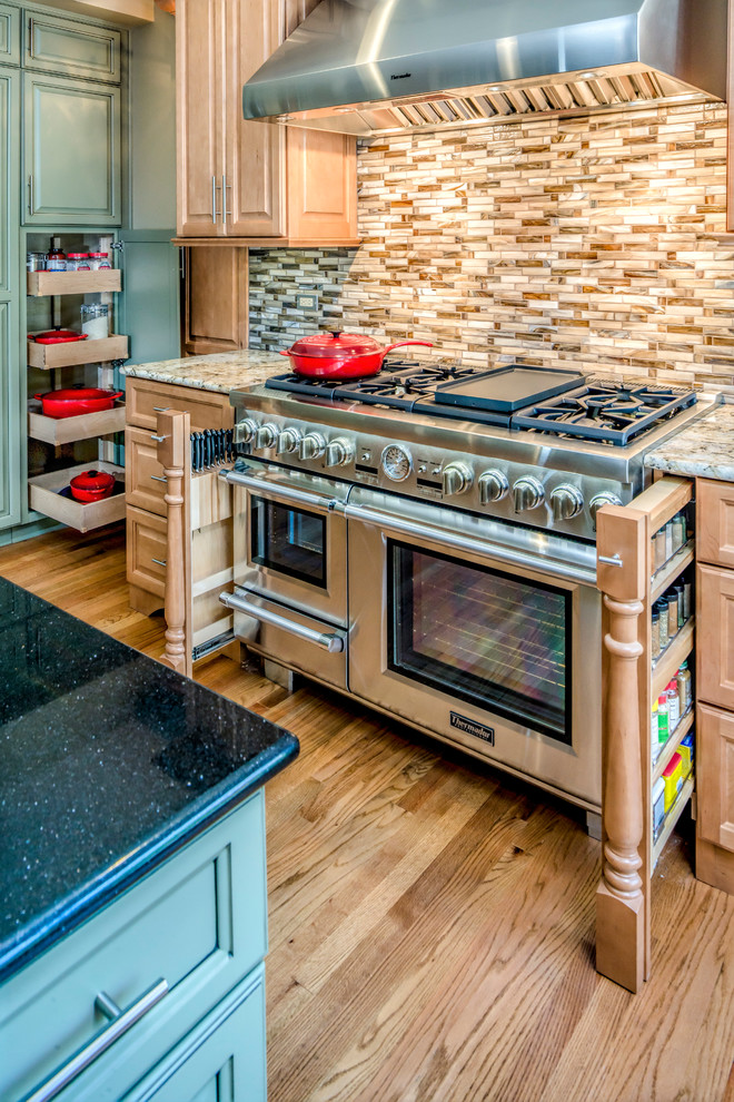 Large eclectic l-shaped open plan kitchen in Chicago with an undermount sink, raised-panel cabinets, green cabinets, granite benchtops, green splashback, glass tile splashback, stainless steel appliances, medium hardwood floors and multiple islands.