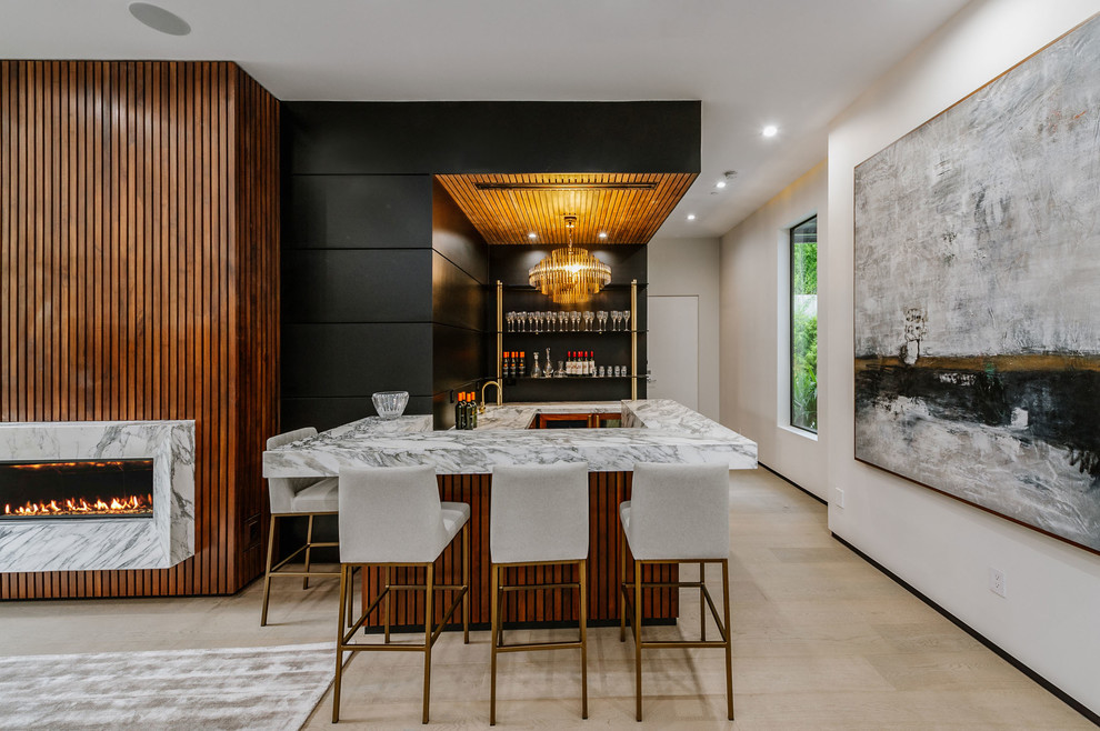 Photo of a large contemporary u-shaped seated home bar in Los Angeles with open cabinets, black cabinets, marble benchtops, light hardwood floors and an integrated sink.