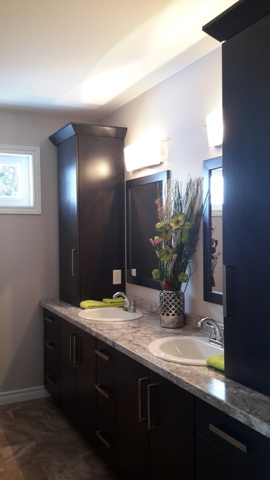 Photo of a traditional bathroom in Toronto with a drop-in sink, flat-panel cabinets, dark wood cabinets, laminate benchtops, an alcove tub, a one-piece toilet, beige tile, ceramic tile, beige walls and ceramic floors.